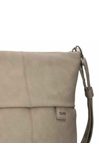 Borsa a spalla in pelle beige con pattina a pieghe, dettagli di cuciture verticali e tracolla regolabile; etichetta del marchio visibile sul lato.