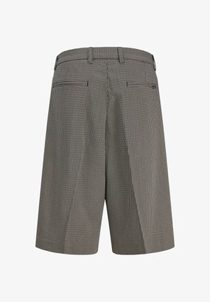 Høytlivs knebukser med svart-hvitt smårutete mønster, beltehemper og to baklommer med spretteåpning.