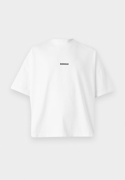 T-shirt en coton blanc à manches courtes et col rond. Présente le texte "BONSAI" en noir centré sur la poitrine. Design simple, sans motifs.