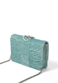 Un bolso de mano texturizado en color teal con una correa de cadena plateada, que presenta un cierre decorado con joyas con piedras azules y verdes.