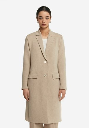 Beige ullkappa med lång ärm, snedkrage och två framfickor. Har två stora knappar och en rak silhuett.