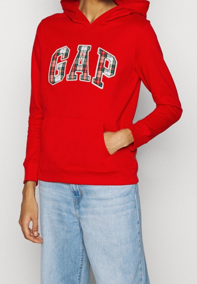 Sudadera roja con capucha y bolsillo frontal, con letras de cuadros que forman la palabra "GAP". Mangas largas y capucha con cordón completan el diseño casual.