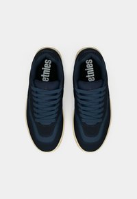 Un paio di sneakers Etnies blu marino con suole beige, viste dall'alto su uno sfondo bianco.