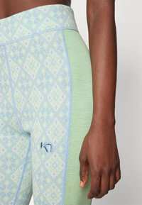 Light green leggings featuring a diamond-patterned design in soft blue and green hues, with a subtle logo on the thigh.