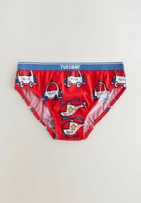 Röda pojkunderkläder har en blå midjeband med "TISDAG"-logotyp och upprepade grafiska motiv av polisbilar och helikoptrar i olika färger.