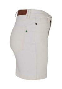 Valged teksapüksid tagatasku, vööltõmmete, metallist nööbi ja pruuni nahast brändiplaadiga vöökohal.