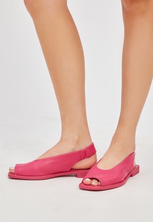 Sandali slingback open-toe in pelle rosa con design minimalista, suola piatta e texture morbida; presentano un'ampia apertura frontale e una fascia sul tallone.