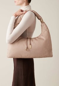 Textured light pink hobo bag with a soft, padded shoulder strap, gold hardware, and a zipper closure. Suitable for casual use.