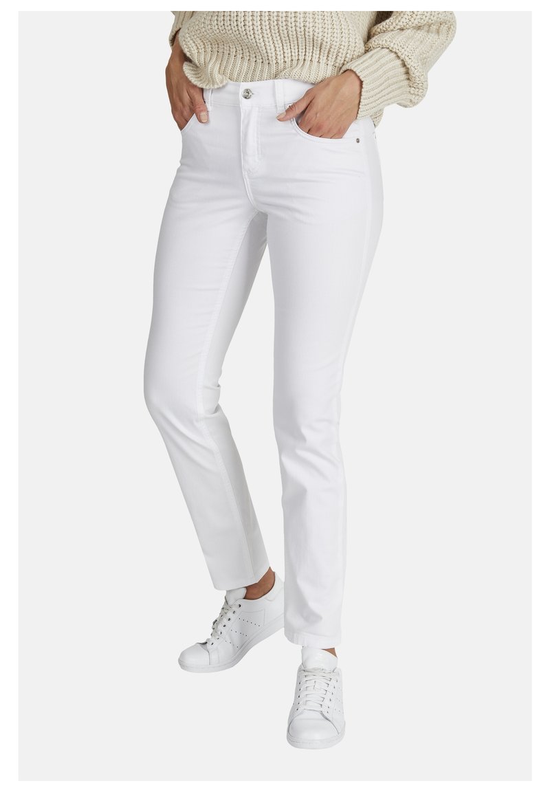 Pantalones jeans de denim blanco con corte ajustado, que cuentan con bolsillos frontales, cierre de botón y pasadores para cinturón, combinados con zapatillas blancas.