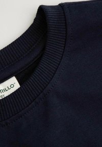 Granatowa bawełniana bluza z prążkowanym, okrągłym dekoltem, cechująca się gładką teksturą oraz widoczną od wewnątrz metką z logo.