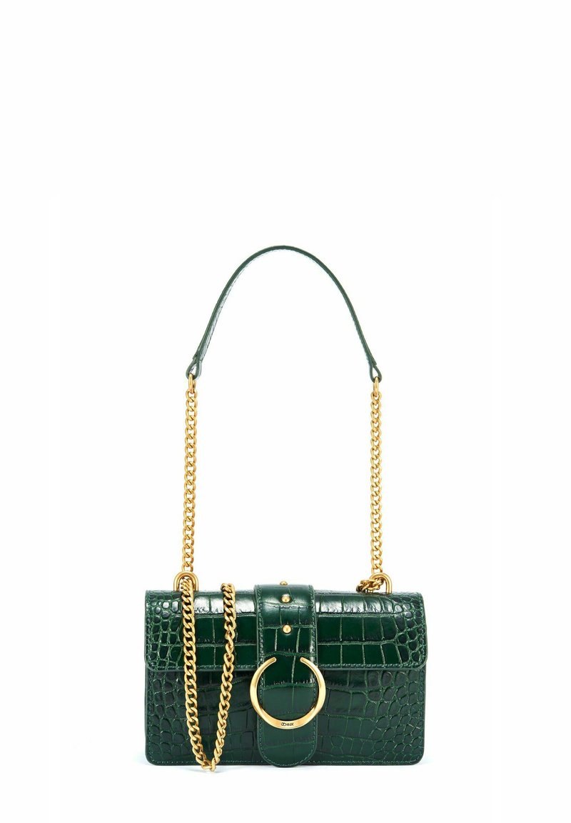Zielona torebka z tłoczonej skóry krokodyla z złotym łańcuchem, prostokątny kształt i okrąły złoty akcent na klamrze.