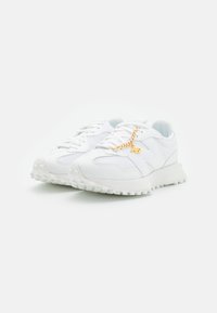 Weiße Sportsneakers aus einem Obermaterial aus Mesh und Leder, mit einer strukturierten Sohle und einem goldenen Kettenakzent an den Schnürsenkeln.