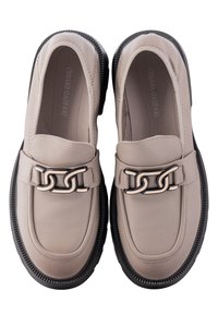 Beige leren loafers met een zwarte rubberen zool, voorzien van een decoratieve kettingaccent op de wreef en een glad bovenwerk.