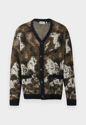 Bruine en crèmekleurige cardigan met patroon, V-hals, zwarte knoopsluitingen en twee voorzakken. Gebreide textuur met contrasterende zwarte afwerking.