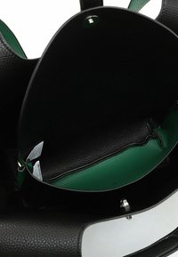 Sac en cuir noir texturé avec intérieur vert. Forme ovale, ouverture en haut, et matériel en argent. Comprend des étiquettes d'entretien visibles à l'intérieur.