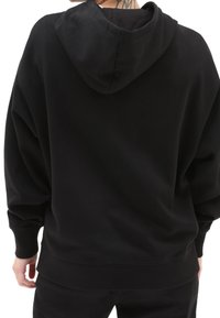 Felpa nera con cappuccio dalla vestibilità comoda, polsini e orlo a coste. Tessuto liscio, design minimalista, senza motivi o loghi visibili.