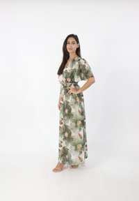 Abito maxi floreale in tessuto leggero con stampa di foglie verdi e fiori beige. Presenta maniche corte a volant e vita cinchata.