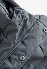 Graue gepolsterte Jacke mit einem Frontreißverschluss, Druckknopf und verstellbarem Kordelzug. Glatte Textur mit gesteppten Nähdetails.