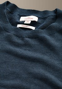 Pull en maille bleu marine avec col rond côtelé, taille moyenne, coupe régulière, étiquette "Next Signature" et fabriqué au Cambodge.