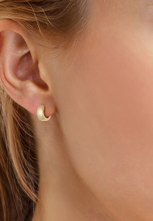 Kuldne kõver kõrva cuff, poleeritud viimistlus, stiilne disain, minimalistlik kuju, mugav sobivus, asetatud kõrvalobe, rõhutades kõrva kontuure.
