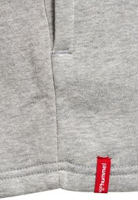 Helle graue Sweatshirt-Stoff mit einer weichen Textur, versehen mit einem roten Hummel-Logo-Tag in der Nähe der Naht und einem schlichten, lässigen Design.