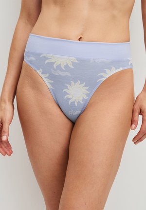 Vrouw draagt lichtblauwe hoog uitgesneden onderbroek met een brede tailleband en gele zon- en golfpatronen.