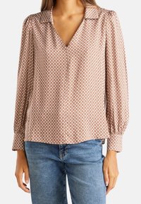 Långärmad blus i brunt med ett geometriskt vitt mönster, med krage och V-urringning; mjukt tyg med en avslappnad passform.