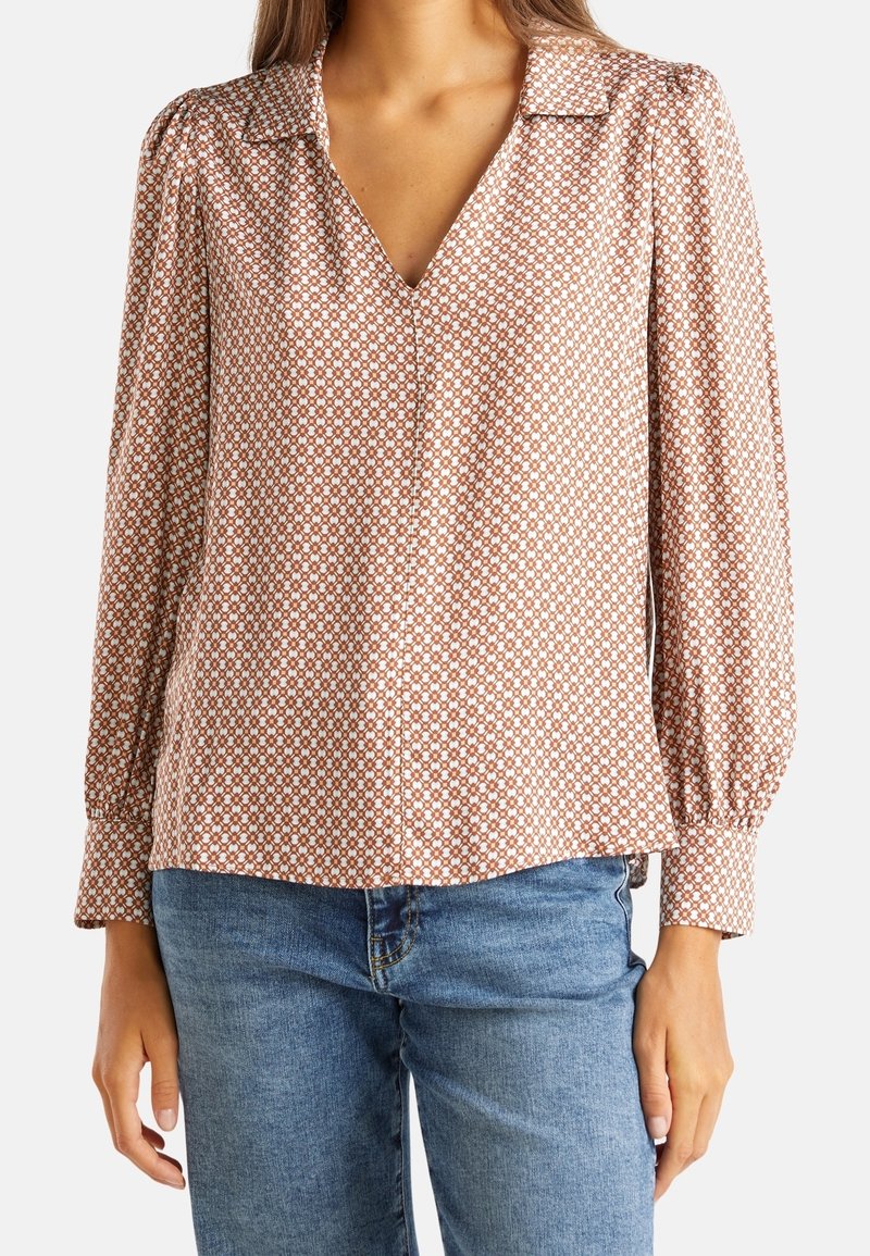 Långärmad blus i brunt med ett geometriskt vitt mönster, med krage och V-urringning; mjukt tyg med en avslappnad passform.