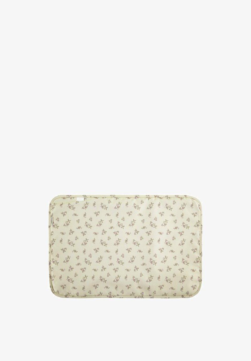 Cojín rectangular beige con bordes redondeados, decorado con un pequeño patrón floral púrpura distribuido de manera uniforme por toda la superficie.