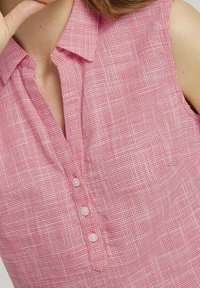 Rotes und weiß kariertes ärmelloses Hemd mit Kragen und drei weißen Knöpfen vorne. Weicher, strukturierter Stoff.