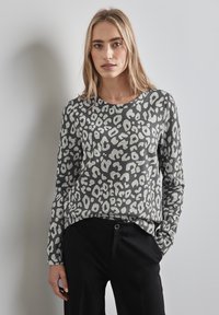 Maglietta grigia a maniche lunghe con un motivo a macchie di leopardo in bianco e nero. Tessuto morbido, scollatura rotonda, vestibilità rilassata, abbinata a pantaloni neri.