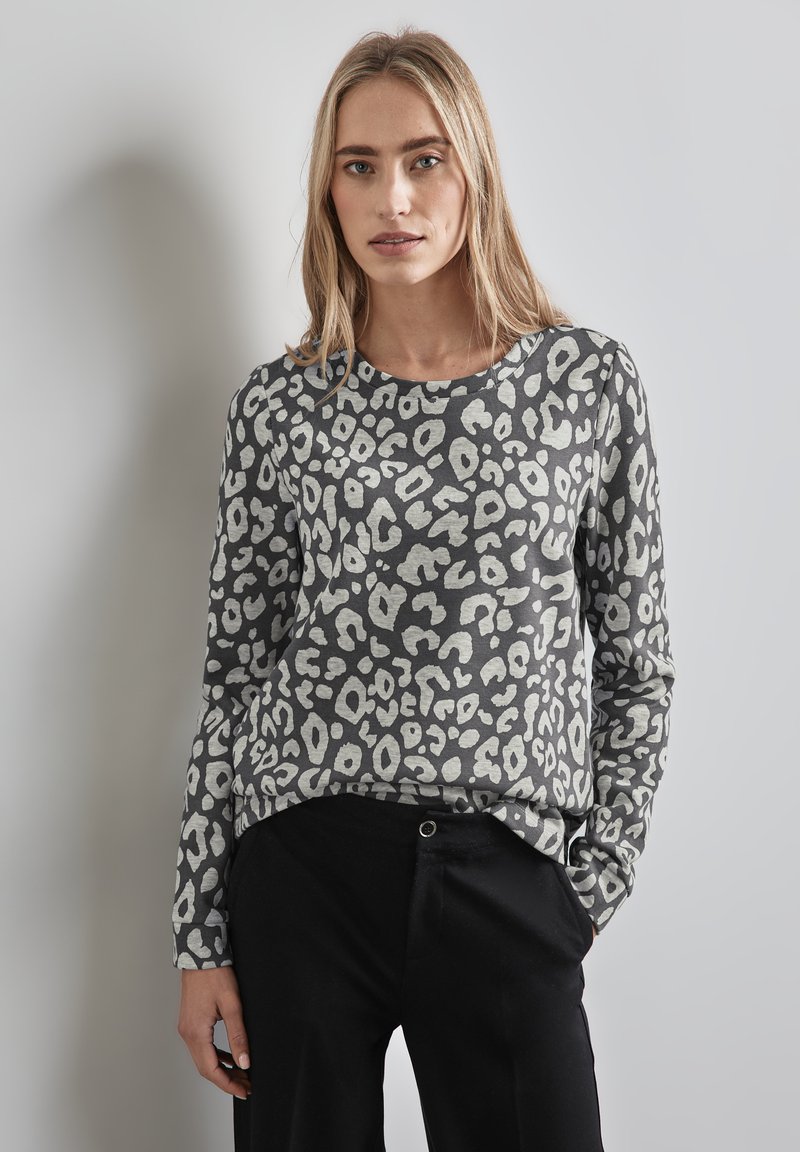 Maglietta grigia a maniche lunghe con un motivo a macchie di leopardo in bianco e nero. Tessuto morbido, scollatura rotonda, vestibilità rilassata, abbinata a pantaloni neri.