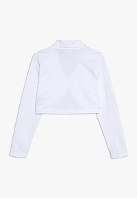 Top bianco a maniche lunghe, svasato e realizzato in un materiale morbido. Presenta un colletto e dettagli di cucitura minimi.