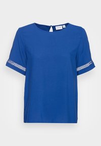 Top blu corto a maniche corte con scollatura tonda e apertura a forma di chiave sul retro. Motivo decorativo bianco sulle maniche. Tessuto morbido e liscio.
