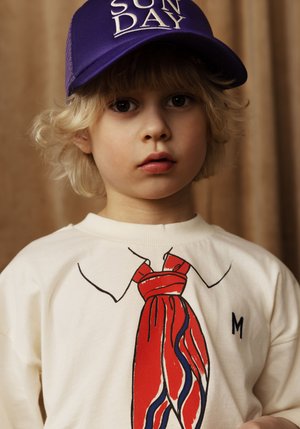 T-shirt crema con grafica astratta di cravatta rossa e contorni neri. Cappellino viola con testo "SUN DAY". Texture morbida, design casual.