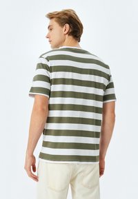 Grøn- og hvidstribet T-shirt lavet af blød bomuld. Den har korte ærmer og rund halsudskæring, med en afslappet pasform.