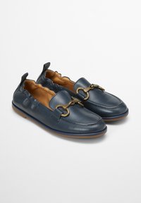 Navy leren instappers met een golvende rand, voorzien van een goudkleurige hardware accent en een lichtbruine binnenkant. Platte rubberen zool.