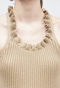 Μπεζ πλεκτό τοπ με ριμπ ύφανση, λαιμόκοψη με βολάν και λεπτές τιράντες, ιδανικό για καθημερινή χρήση.