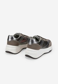 Un par de zapatillas grises y metálicas con suelas blancas gruesas, mostradas desde atrás sobre un fondo blanco.