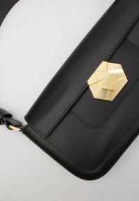 Borsa a tracolla in pelle nera con una chiusura geometrica in oro, forma rettangolare, design elegante e tracolla piatta per il trasporto a spalla.