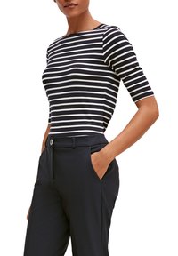 Haut à rayures bleu marine et blanc à manches courtes avec un col rond, associé à un pantalon sombre ajusté avec poches et fermeture à bouton.