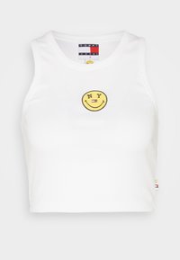 Bílý zkrácený top z ribbovaného materiálu, se žlutým smajlíkem a textem "NY" a malou logovací etiketou na lemu.