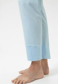 Jasnoniebieskie spodnie od piżamy z białymi pionowymi paskami, z jednolitym jasnoniebieskim mankietem na dole. Miękki materiał, dopasowany krój.