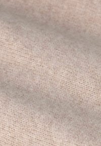 Tissu tricoté beige clair, présentant une texture douce avec un motif subtil. Le matériau semble lisse et légèrement extensible.