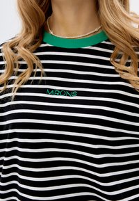 Zwart-witte gestreepte t-shirt met een groene geribde kraag; beschikt over "MIRONS" geborduurd in het groen op de borst. Zachte, rekbare stof.