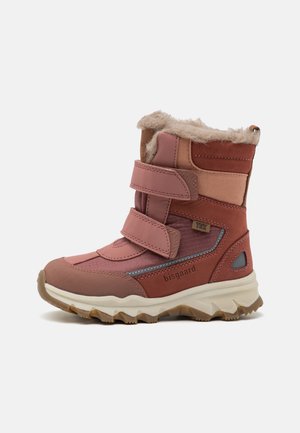 Bota infantil rosa claro com fechos de velcro, forro de pele macia, sola de borracha, material texturizado e detalhes cinzas.