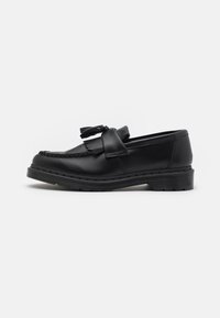 Mocasín de cuero negro con un acento de borlas, detalles de costura a lo largo del borde y una suela de goma gruesa para mayor durabilidad.