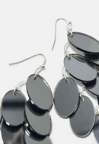 Czarne owalne kolczyki z błyszczącymi metalicznymi powierzchniami, połączone srebrnymi elementami, z zapięciem w formie haka dla łatwego noszenia.