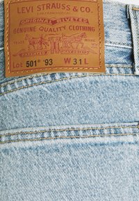 Kožená etiketa Levi Strauss & Co. na světle modrých džínách z bavlny s velikostí W31 L a Lot 501 '93 s klasickými švy.