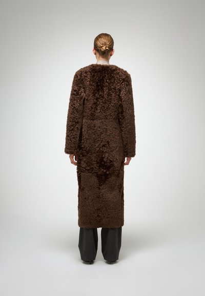 Bruine vacht lange jas met een gestructureerde afwerking, met een rechte snit en wijde mouwen, gecombineerd met donkergrijze broek.